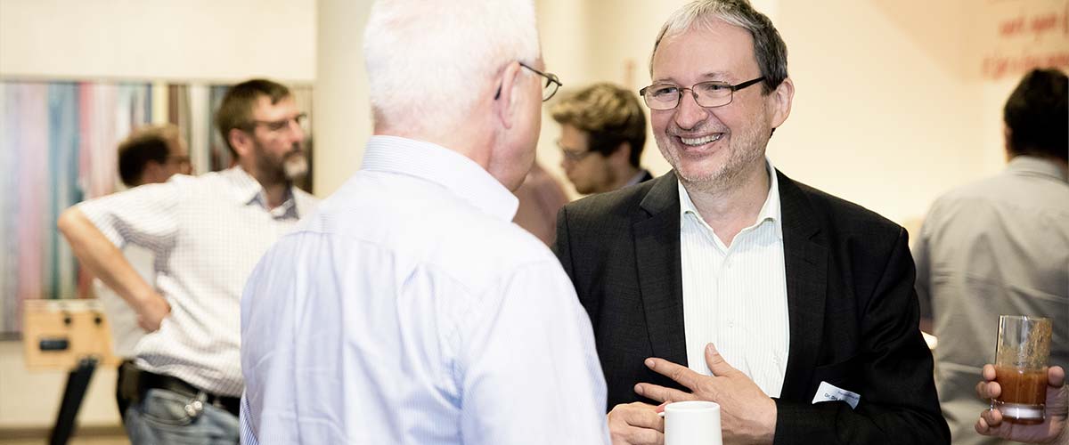 Sachverständiger Dr. Schoeps lächelt bei einem Gespräch im Meeting
